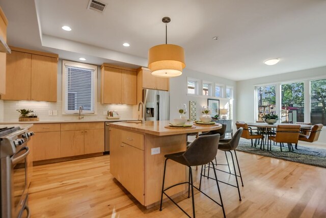 kitchen featuring stainless steel appliances, visible vents, light wood-type flooring, and light brown cabinets