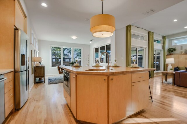 kitchen featuring recessed lighting, appliances with stainless steel finishes, a sink, and light wood-type flooring