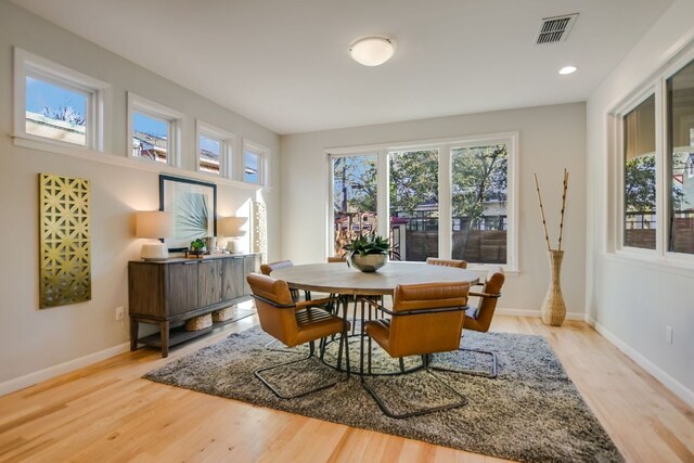 dining room featuring a healthy amount of sunlight, baseboards, light wood finished floors, and visible vents
