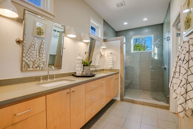 bathroom featuring visible vents, a sink, double vanity, and a shower stall