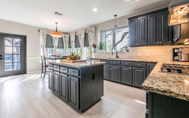3809 Bent Brook Dr, Round Rock, TX 78664 - kitchen with custom exhaust hood, stainless steel gas stovetop, tasteful backsplash, light stone counters, and recessed lighting