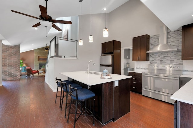 kitchen with stainless steel electric stove, wall chimney range hood, freestanding refrigerator, light countertops, and high vaulted ceiling