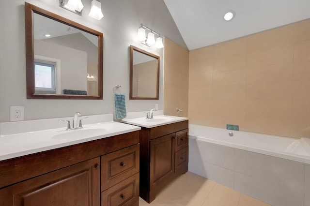 full bathroom with a relaxing tiled tub, two vanities, vaulted ceiling, and tile patterned floors