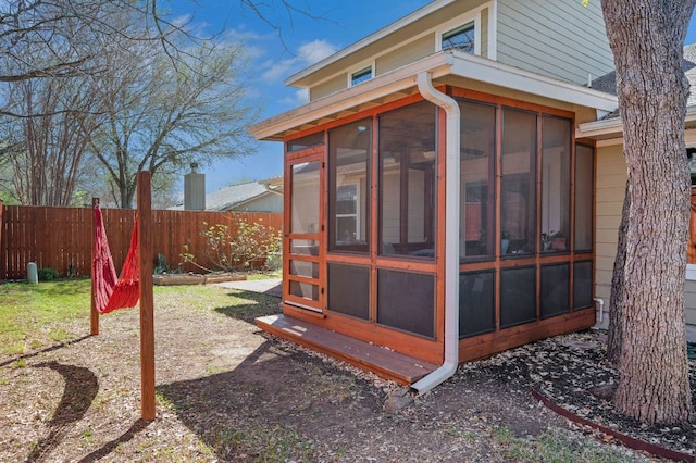 view of home's exterior featuring a sunroom and fence