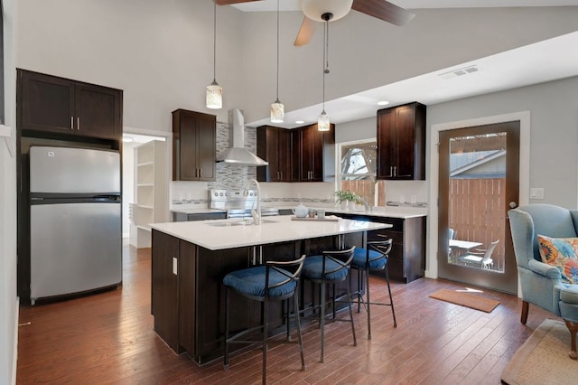 11214 Stormy Ridge Rd, Austin, TX 78739 - kitchen featuring freestanding refrigerator, wall chimney exhaust hood, dark wood-style floors, light countertops, and a towering ceiling
