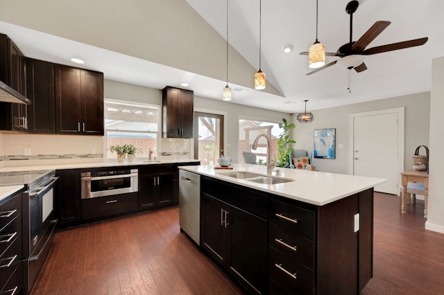 kitchen featuring appliances with stainless steel finishes, a sink, vaulted ceiling, a ceiling fan, and tasteful backsplash