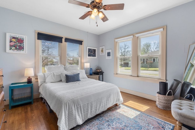 bedroom featuring baseboards, wood finished floors, and a ceiling fan
