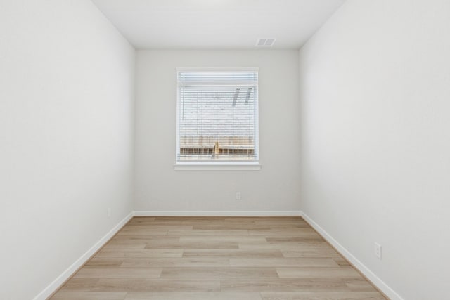 empty room with visible vents, light wood-style floors, and baseboards