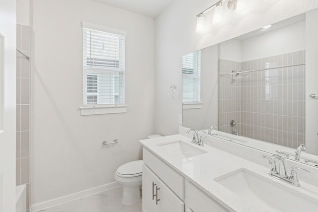 full bath with a sink, baseboards, toilet, and double vanity