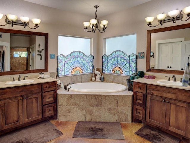 full bath with a sink, a bath, two vanities, and a chandelier