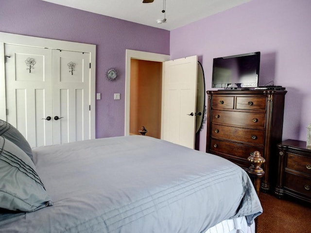 bedroom with dark carpet, a closet, and a ceiling fan