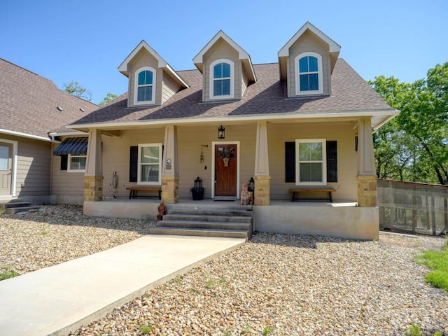 view of front of house with roof with shingles, covered porch, and stone siding