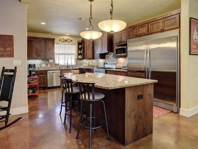 kitchen featuring tasteful backsplash, baseboards, a kitchen island, and built in appliances