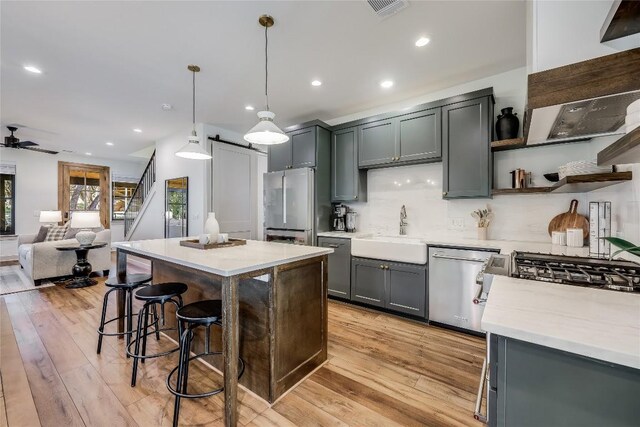 7601 Bar K Ranch Rd, Lago Vista, TX 78645 - kitchen with stainless steel appliances, light wood finished floors, open shelves, a kitchen island, and recessed lighting