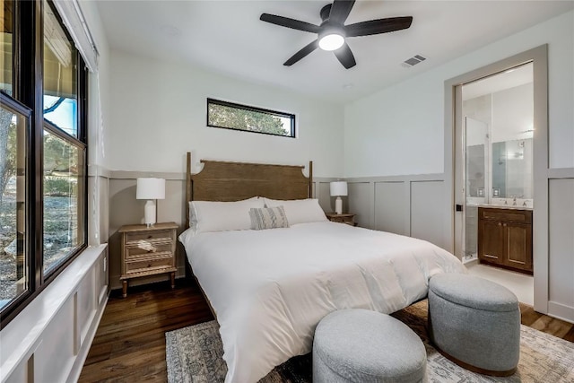 7601 Bar K Ranch Rd, Lago Vista, TX 78645 - bedroom with dark wood-type flooring, connected bathroom, a ceiling fan, and wainscoting