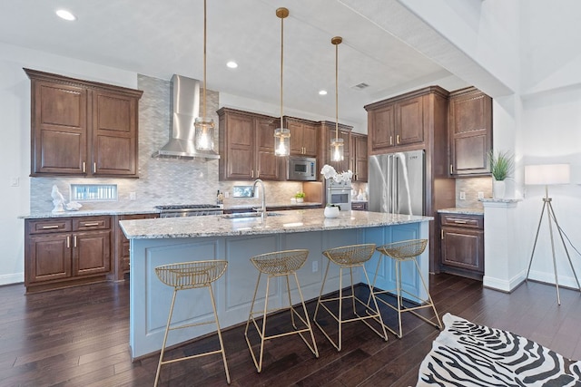 510 Doe Whisper Way, Austin, TX 78738 - kitchen with wall chimney exhaust hood, appliances with stainless steel finishes, dark wood-style floors, decorative backsplash, and a breakfast bar