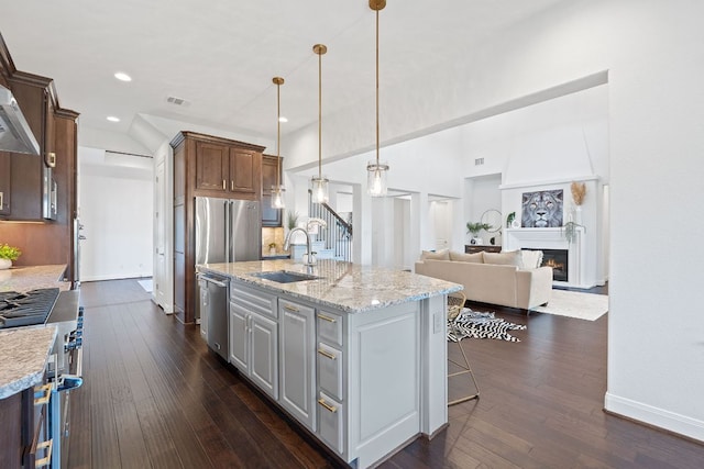 510 Doe Whisper Way, Austin, TX 78738 - kitchen featuring range, dishwasher, a lit fireplace, a kitchen island with sink, and dark wood-style flooring