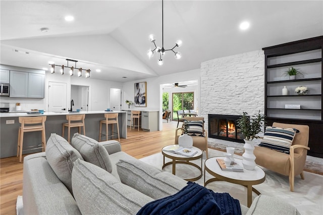 1004 Cripple Creek Dr, Austin, TX 78758 - living area featuring high vaulted ceiling, light wood-style floors, ceiling fan with notable chandelier, and a stone fireplace