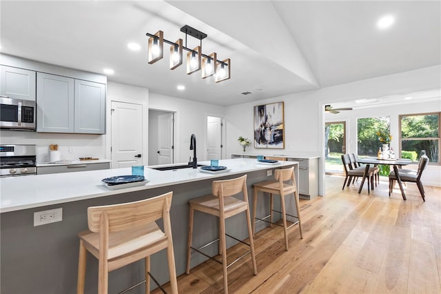 1004 Cripple Creek Dr, Austin, TX 78758 - kitchen with light countertops, a sink, a kitchen breakfast bar, light wood-style flooring, and stainless steel appliances