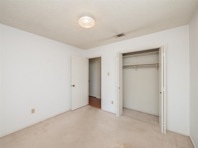unfurnished bedroom featuring carpet floors, a closet, visible vents, and a textured ceiling