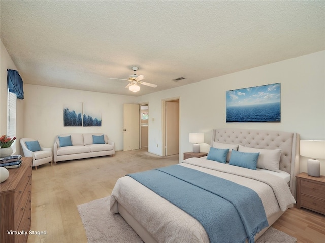 bedroom featuring a textured ceiling, wood finished floors, a ceiling fan, and visible vents