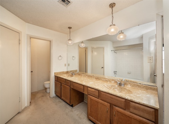 bathroom featuring a textured ceiling, visible vents, toilet, a sink, and double vanity