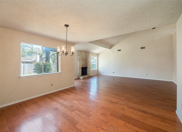 unfurnished living room featuring a textured ceiling, wood finished floors, a notable chandelier, and baseboards