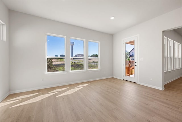 empty room with baseboards, recessed lighting, and light wood-style floors