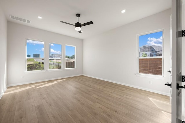 spare room with baseboards, a ceiling fan, visible vents, and light wood-style flooring