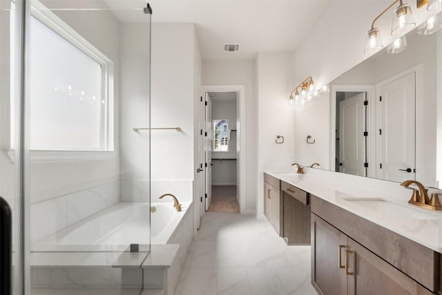 bathroom featuring marble finish floor, double vanity, visible vents, a sink, and a bath