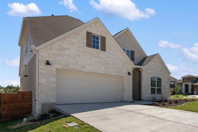 view of front of house with stone siding, fence, roof with shingles, and concrete driveway