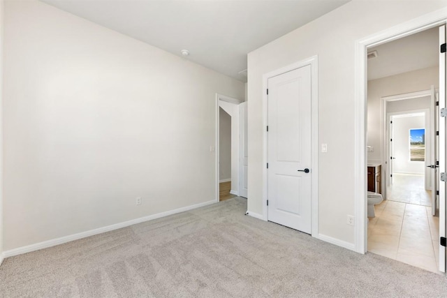unfurnished bedroom featuring light carpet, baseboards, and connected bathroom