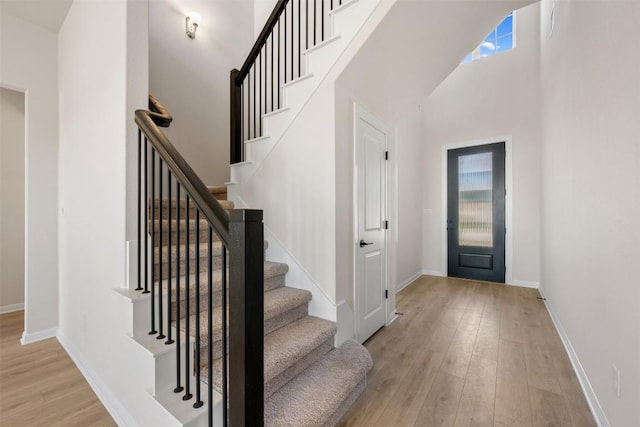 entryway featuring baseboards, light wood finished floors, and stairs