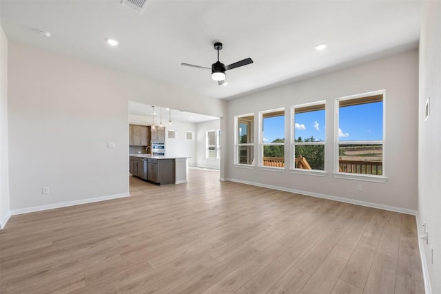 unfurnished living room with light wood-style floors, visible vents, a ceiling fan, and baseboards