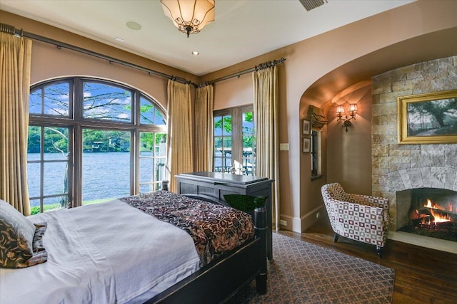 6704 Pixie Cv, Austin, TX 78746 - bedroom with hardwood / wood-style floors, arched walkways, a water view, and a fireplace