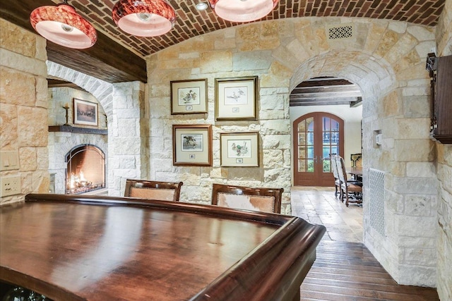 6704 Pixie Cv, Austin, TX 78746 - dining area featuring arched walkways, lofted ceiling, brick ceiling, hardwood / wood-style floors, and a fireplace