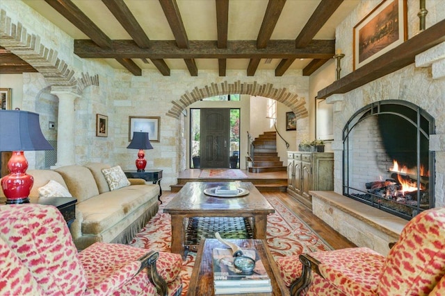 6704 Pixie Cv, Austin, TX 78746 - living room featuring hardwood / wood-style flooring, a warm lit fireplace, arched walkways, and beam ceiling
