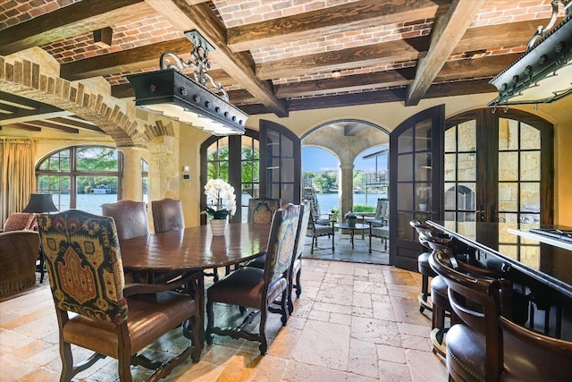 6704 Pixie Cv, Austin, TX 78746 - dining space featuring stone tile flooring, beam ceiling, a water view, brick ceiling, and decorative columns