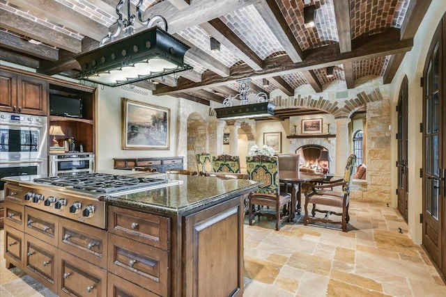 6704 Pixie Cv, Austin, TX 78746 - kitchen with appliances with stainless steel finishes, beam ceiling, arched walkways, stone tile flooring, and dark stone countertops