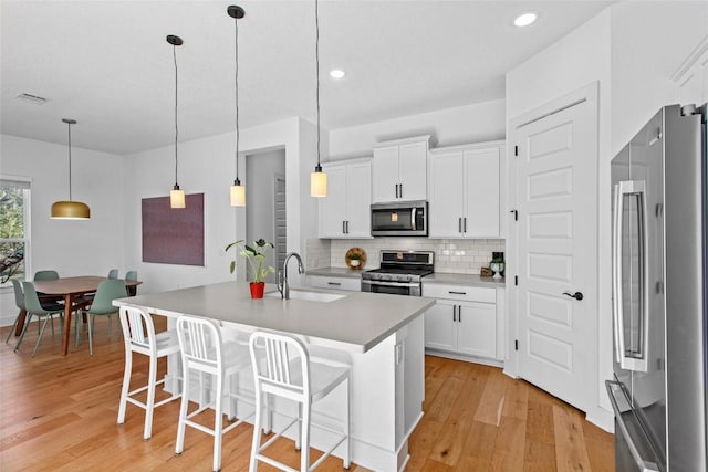 130 Volterra Ln, Dripping Springs, TX 78620 - kitchen with stainless steel appliances, tasteful backsplash, light wood-style floors, white cabinetry, and recessed lighting