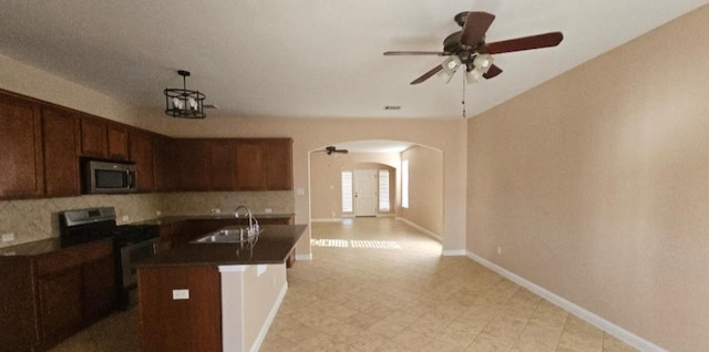 19500 Moorlynch Ave, Pflugerville, TX 78660 - kitchen with stainless steel appliances, arched walkways, dark countertops, and tasteful backsplash