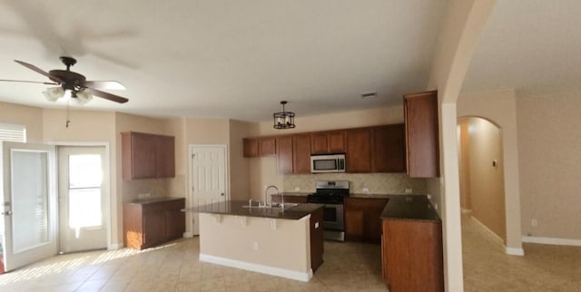 19500 Moorlynch Ave, Pflugerville, TX 78660 - kitchen with stainless steel appliances, dark countertops, tasteful backsplash, arched walkways, and plenty of natural light