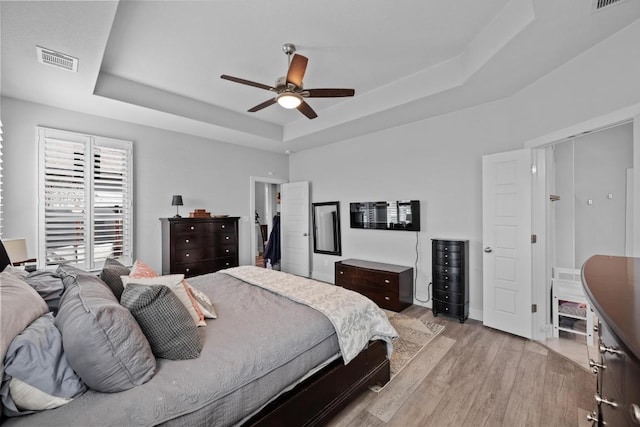 217 Palio Pl, Georgetown, TX 78628 - bedroom featuring a raised ceiling, light wood-style flooring, and a ceiling fan