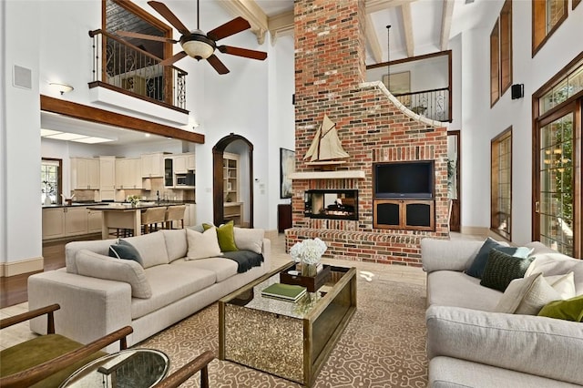 114 Flying Scot St, Lakeway, TX 78734 - living area featuring a ceiling fan, a towering ceiling, beamed ceiling, a fireplace, and arched walkways