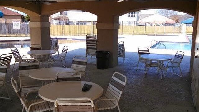 13217 Perconte Dr, Del Valle, TX 78617 - fenced backyard with a ceiling fan, outdoor dining area, and a community pool