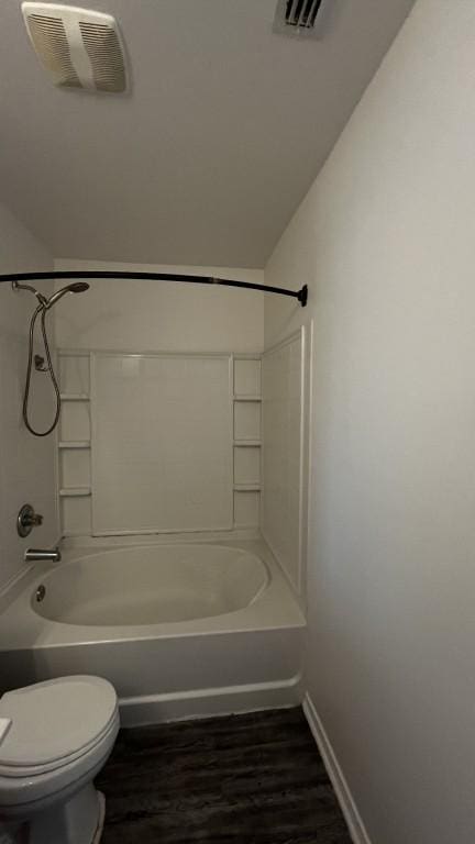 13217 Perconte Dr, Del Valle, TX 78617 - bathroom featuring wood finished floors, toilet, washtub / shower combination, and baseboards