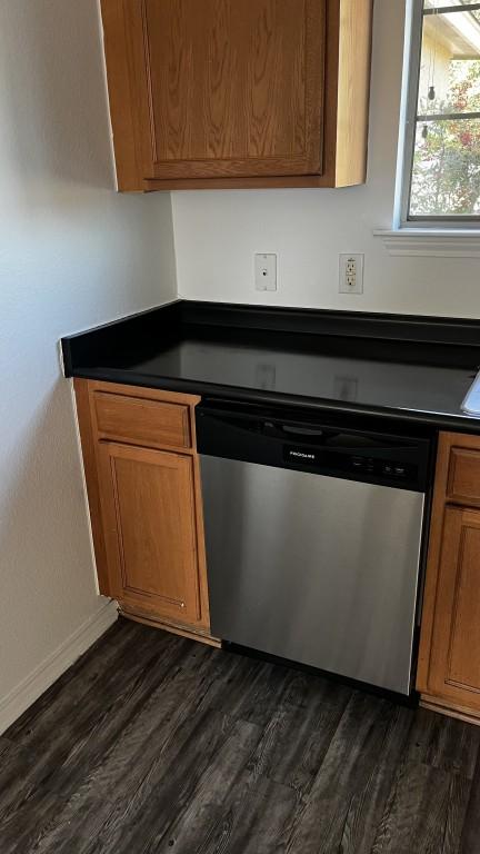 13217 Perconte Dr, Del Valle, TX 78617 - kitchen featuring stainless steel dishwasher, dark countertops, brown cabinets, and dark wood-style floors