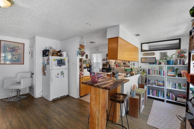 1905 Chestnut Ave, Austin, TX 78722 - kitchen featuring freestanding refrigerator, dark wood finished floors, wood counters, a textured ceiling, and brown cabinetry