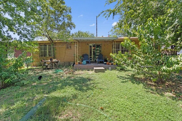 1905 Chestnut Ave, Austin, TX 78722 - back of house with a patio, brick siding, and a yard