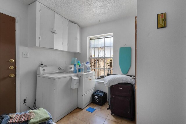 1905 Chestnut Ave, Austin, TX 78722 - washroom featuring washer and dryer, a textured ceiling, cabinet space, and light tile patterned flooring